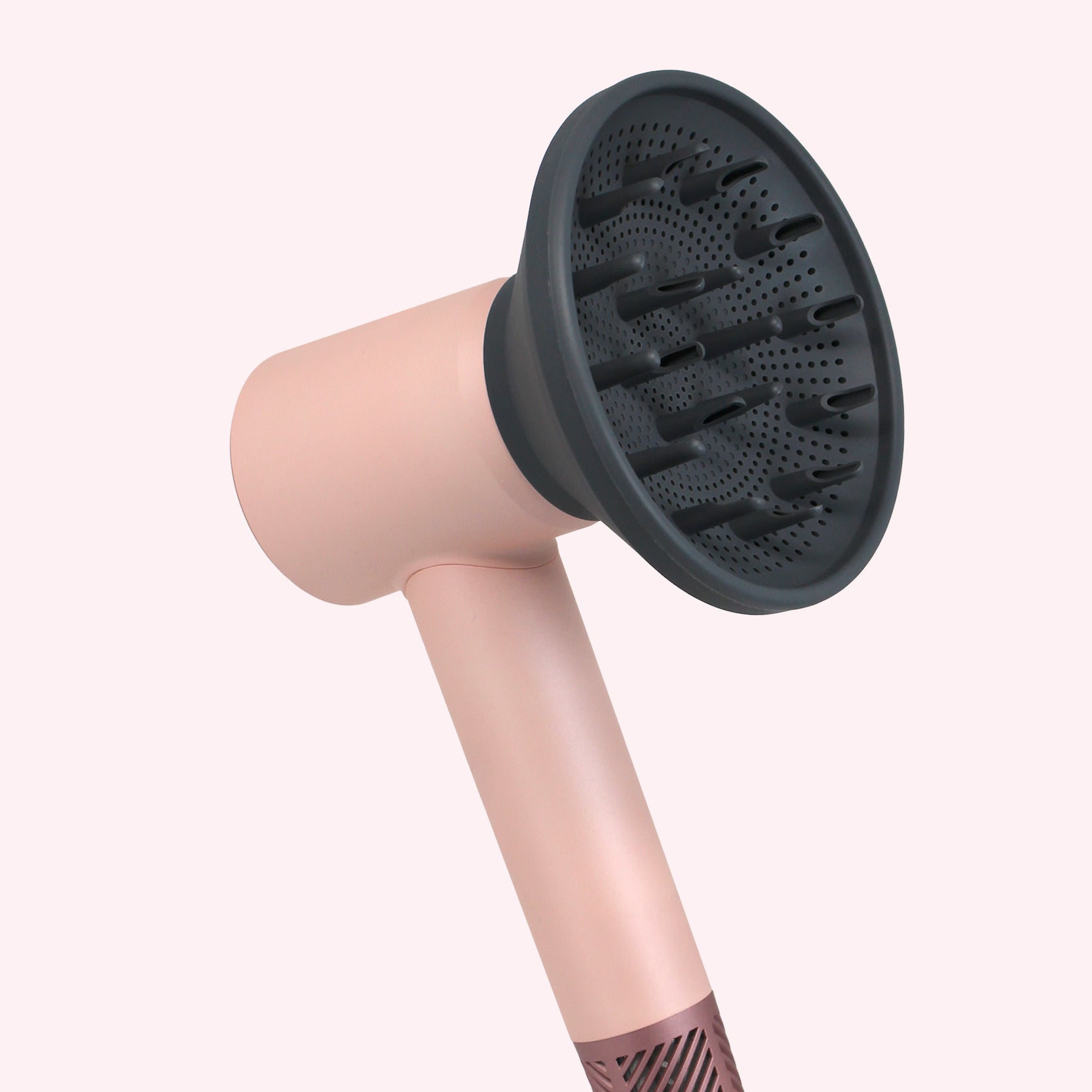 Pink hair dryer with a black diffuser attachment on a white background