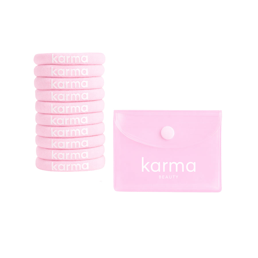 A set of ten light pink silicone nail wraps stacked on the left, next to a matching light pink silicone pouch with a snap button closure. The brand name 'karma BEAUTY' is printed in white on both the wraps and the pouch.