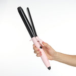 Pink and black hair curler held by a hand on a white background