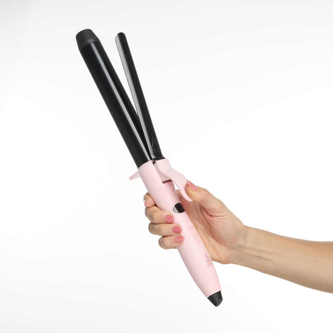 Pink and black hair curler held by a hand on a white background